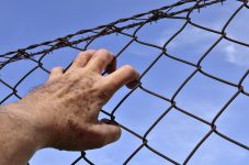Prisoner hand on barbed wire fence