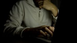 Man on laptop in dark room