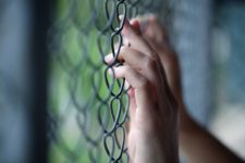 Hand holding onto detention fence