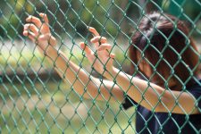 Woman holding onto prison fence