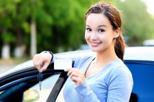 Young woman driver smiling with car licence and key