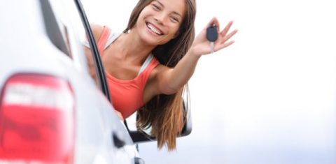 Young woman driver showing car keys