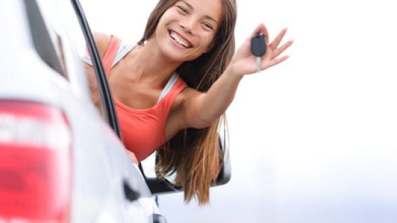 Young woman driver showing car keys