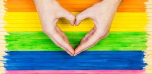 Gay flag and hands forming a heart