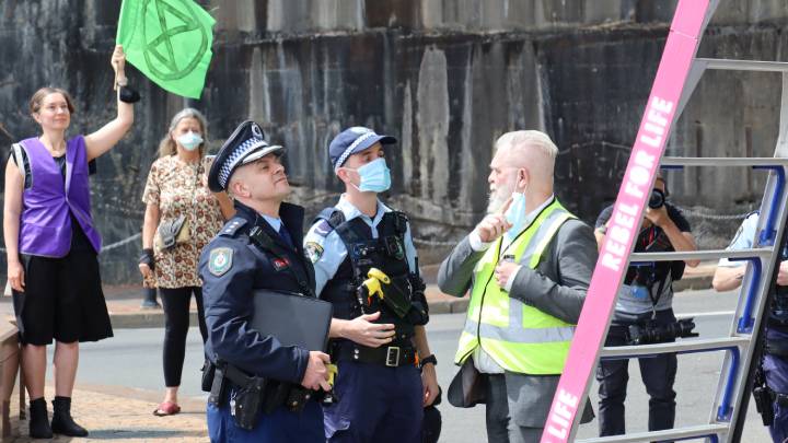 Police confer with an XR rebel