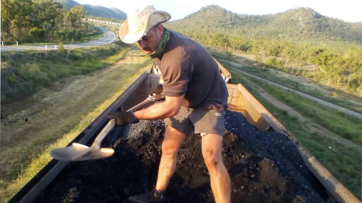 Kyle Magee shovels Adani’s coal out of its train and onto the ground below