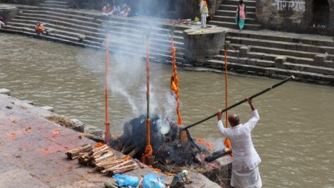 A cremator monitors a burning funeral pyre