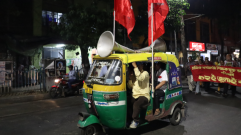 A man inside an autorickshaw adorned with loudspeakers alerts passers-by to the reason for the demonstration