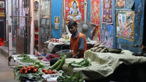 A greengrocer in his usual spot adorned with images of Hindu deities