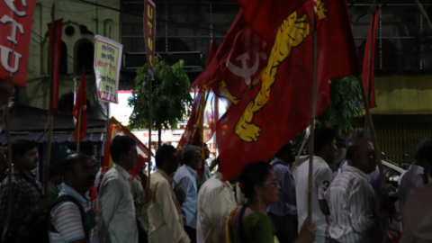 Hundreds of union members march beneath red flags