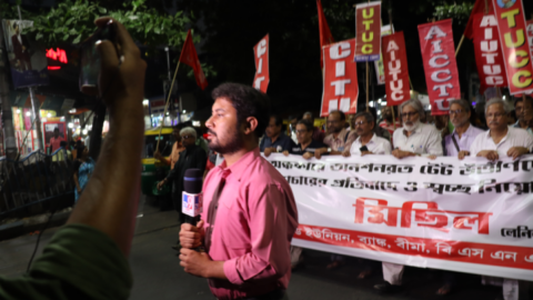 A television reporter moves quickly as the protesters progress behind him