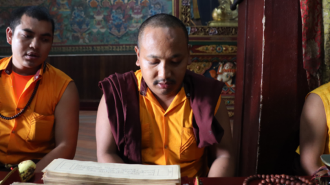 A Tibetan monk recites prayers in a monastery just across from the stupa