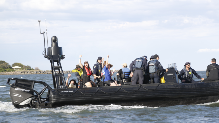 Arrested climate defenders defiant in the back of the police boat. Photo credit Green Left Weekly journalist Alex Banbridge