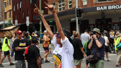 Gomeroi activist Gwenda Stanley signals the crowd as thousands descend upon Broadway