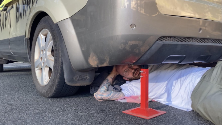 Disrupt Burrup Hub campaigner Maz Misiewicz locked onto a concrete barrel in a station wagon blocking a Perth CBD road on 11 December 2023