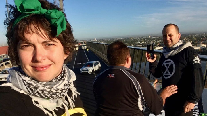 XR climate defenders Violet CoCo Joe Zammit and Brad Homewood blocking traffic to sound the climate alarm on 5 March