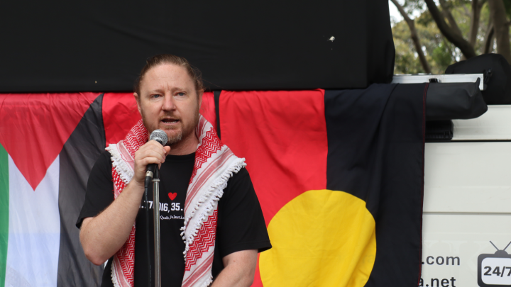 Palestine Action Group organiser Josh Lees tells the crowd that governments globally are now trying to renormalise Israel, despite it having just perpetrated 25 months of mass slaughter